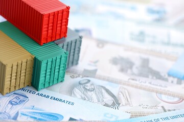 United Arab Emirates dirham currency money bills and toy cargo containers. The concept of shipping and logistics