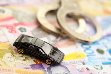 Philippines peso currency money bills and toy car with handcuffs. The concept of car accident