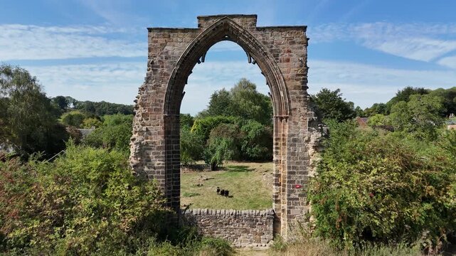 Dale Abbey, Derbyshire, England - August 25 2025: Drone footage captures the historic ruins of Dale Abbey, showcasing the stone archway and surrounding countryside.