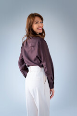 Studio shot of a brunette haired woman in business casual standing against isolated background with...