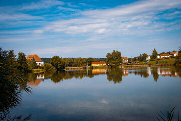 Fototapeta premium Tranquil Boskovštejn pond in South Moravia, Czech Republic, surrounded by greenery and rural landscape.