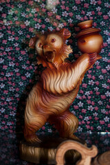 Statue of a bear made of wood on a background of flowers
