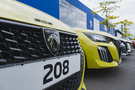 Row of new Peugeot 208 cars displayed for sale outside a dealership