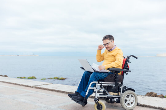 businessman on a wheelchair at a window uses smartphone - Powered by Adobe