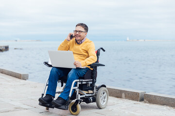 businessman on a wheelchair at a window uses smartphone 4k