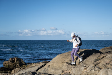 a woman hiking by the ocean on rocky terrain