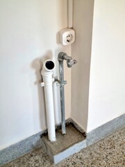 Indoor Plumbing Pipes and Electrical Outlet on White Wall Background