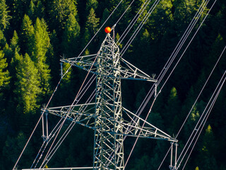 Aerial view of power line pylon in mountaineous area in Switzerland through valley in Canton of Valais.