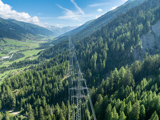 Aerial view of power line pylon in mountaineous area in Switzerland through valley in Canton of Valais.