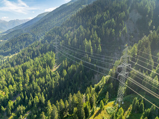 Aerial view of power line pylon in mountaineous area in Switzerland through valley in Canton of Valais.