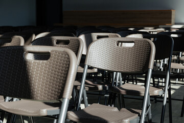 Rows of empty plastic chairs waiting for an event to unfold in a bright, spacious room