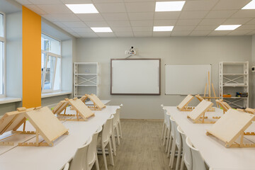 Art studio filled with easels ready for a creative session in a modern classroom setting