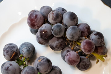 Fresh grapes on a white plate, showcasing their rich color and texture, suitable for culinary contexts or healthy lifestyle themes. Perfect for food photography.