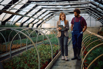 Insurance agent using touchpad during a meeting with a farmer at plant nursery.