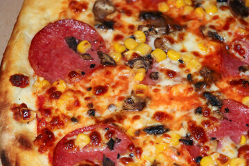 Close-up of a delicious pizza topped with pepperoni, mushrooms, and corn, showcasing a golden, crispy crust and melted cheese, ideal for food enthusiasts and culinary promotions.