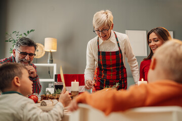 Grandmother serving christmas dinner to family at home