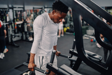 Determined athlete performing dips on parallel bars in gym