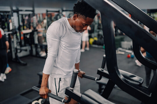 Determined athlete performing dips on parallel bars in gym