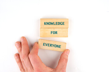 Learning for Everyone concept. Words KNOWLEDGE FOR EVERYONE made from blocks by hand on a light background, top view