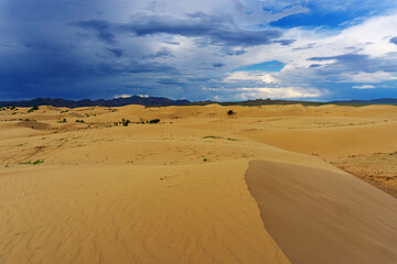 Sand dunes with storm clouds at sunset