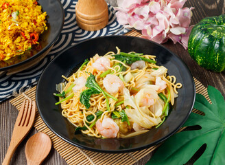 Stir fried noodles with shrimp, fresh vegetables, and chili in a rustic bowl side view of hong kong...