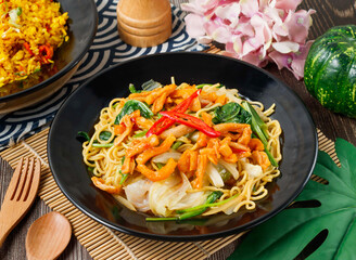 Spicy stir fried vegetable noodles with red chili and fresh herbs in bowl side view of hong kong food