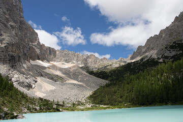 Photography of Lago di Sorapis, Italy, showing the turquoise glacial lake surrounded by Dolomite mountains, pine forests, and dramatic alpine scenery.