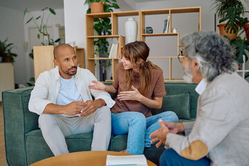Young couple sitting together on a comfortable sofa, engaging in a thoughtful conversation with a...