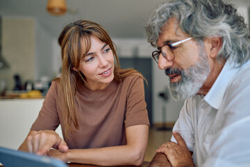 Financial advisor discussing financial strategies with senior man while showing tablet at home,...