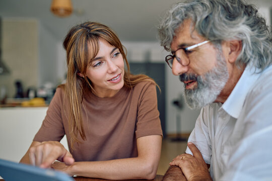Financial advisor discussing financial strategies with senior man while showing tablet at home, fostering trust and connection in planning