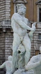 Rome, Italy - 10 January 2025. A powerful male statue at Piazza Navona holds a sea creature as water flows from a fish at his feet in the Fontana del Moro.
