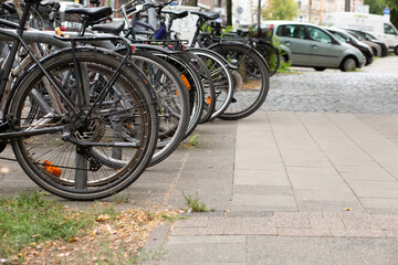 Close-up view of bicycle wheels standing in row on a city street.