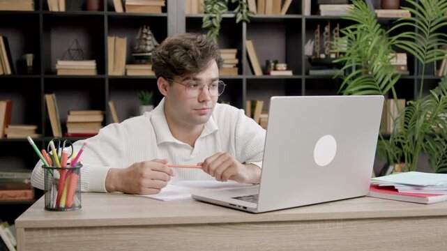 Young boy stares at a computer screen and smiles discreetly. Handsome boy attends a refresher course and listens attentively to the information on the laptop