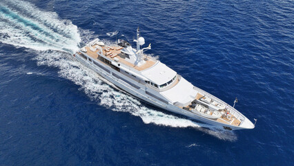 Aerial drone tracking photo of super yacht with wooden deck cruising deep blue Aegean Sea