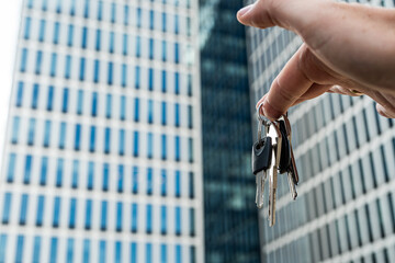 Unlocking New Opportunities – Keys Held in Hand with Modern Business Towers in Background. A...