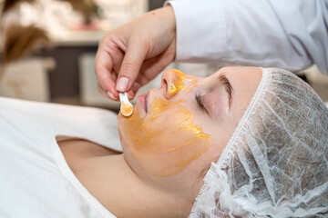 Young caucasian woman getting facial care by beautician at spa salon