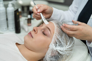 Fototapeta premium Young pretty woman receive rejuvenation beauty procedure face peeling procedure in beauty salon.