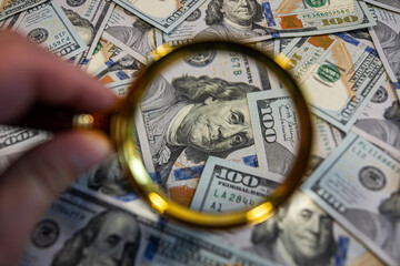 Magnifying glass over dollar bills – Financial audit, money analysis or fraud investigation...