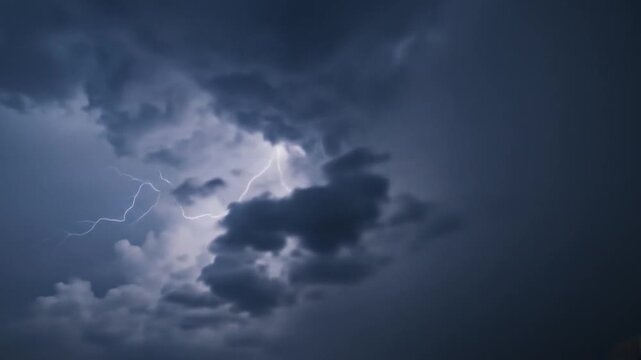 Dramatic lightning strikes illuminate dark storm clouds in a moody sky, creating a powerful atmosphere