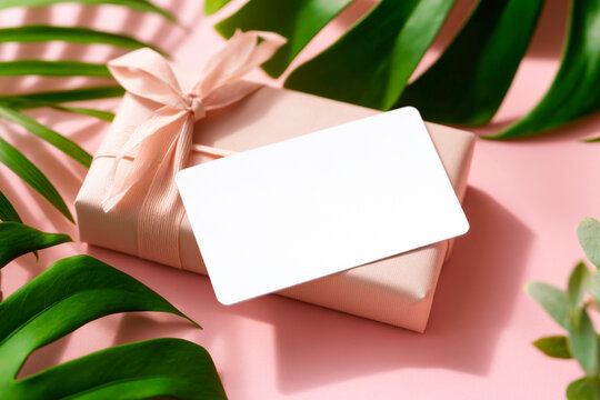 A minimalist and elegant blank notecard mockup placed beside a wrapped gift perfect for a personalized message invitation or holiday greeting