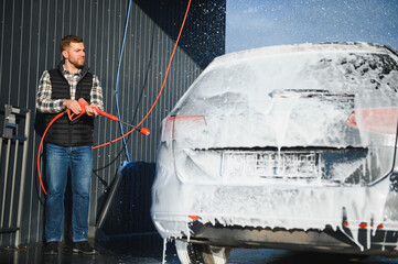 Car wash equipment. A man is washing a car at self service car wash. High pressure vehicle washer...