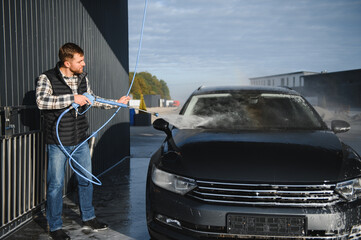 A man washes his car at a car wash. Self service car wash.