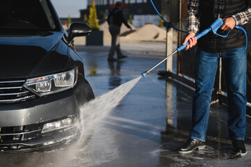 Fototapeta premium Car wash. Man washes car with water from high pressure washer