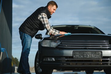 Male wiping car with microfiber cloth closeup. Car wash concept