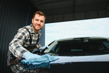 Car detailing - the man holds the microfiber in hand and polishes the car. Selective focus