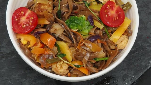 Schezwan Noodles or Vegetable Hakka Noodles or Chow Mein in white bowl. Schezwan Noodles is indo-chinese cuisine hot dish with udon noodles, vegetables and chilli sauce with meat, Japanese food