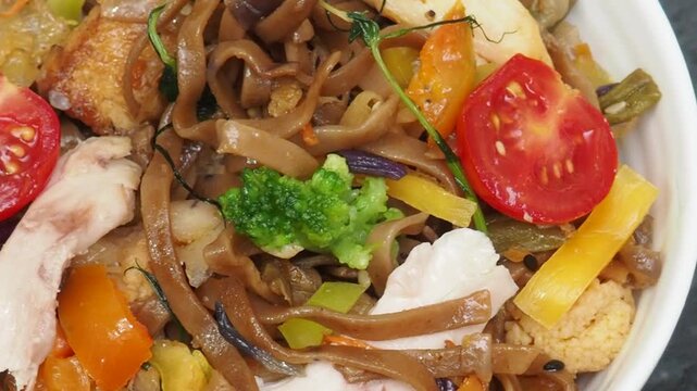 Schezwan Noodles or Vegetable Hakka Noodles or Chow Mein in white bowl. Schezwan Noodles is indo chinese cuisine hot dish with udon noodles, vegetables and chilli sauce with meat, Japanese food