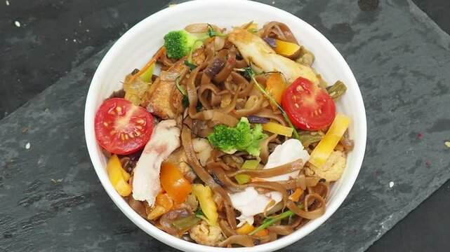 Schezwan Noodles or Vegetable Hakka Noodles or Chow Mein in white bowl. Schezwan Noodles is indo chinese cuisine hot dish with udon noodles, vegetables and chilli sauce with meat, Japanese food