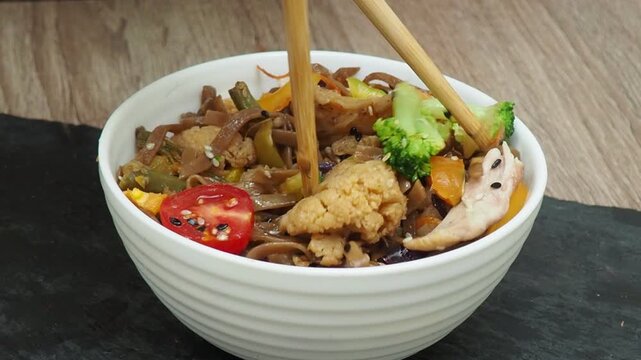 boy eatSchezwan Noodles or Vegetable Hakka Noodles or Chow Mein in white bowl. Schezwan Noodles is indo-chinese cuisine hot dish with udon noodles, vegetables and chilli sauce with meat, Japanese food