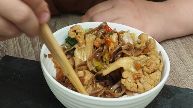 Schezwan Noodles or Vegetable Hakka Noodles or Chow Mein in white bowl. Schezwan Noodles is indo-chinese cuisine hot dish with udon noodles, vegetables and chilli sauce with meat, Japanese food